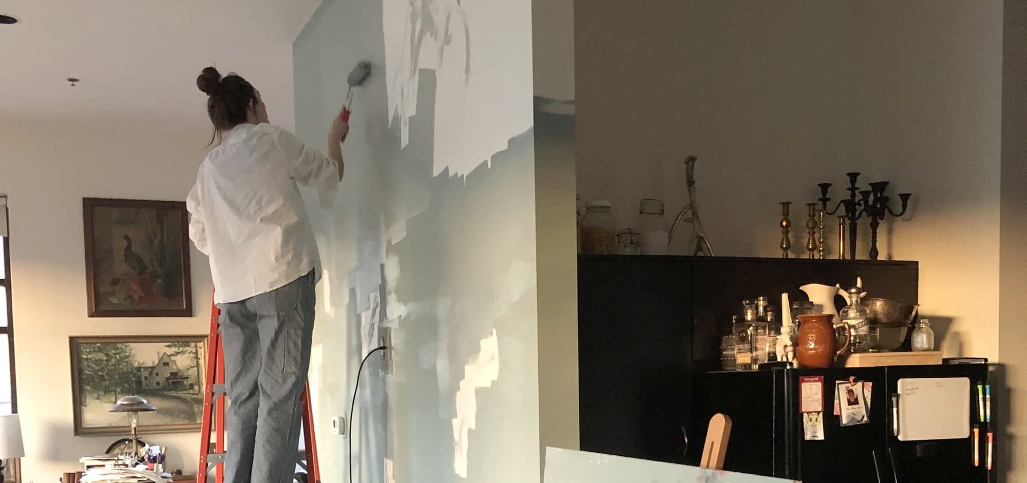 Haley roller-painting a wall on the left of a split image with antique home belongings on the right