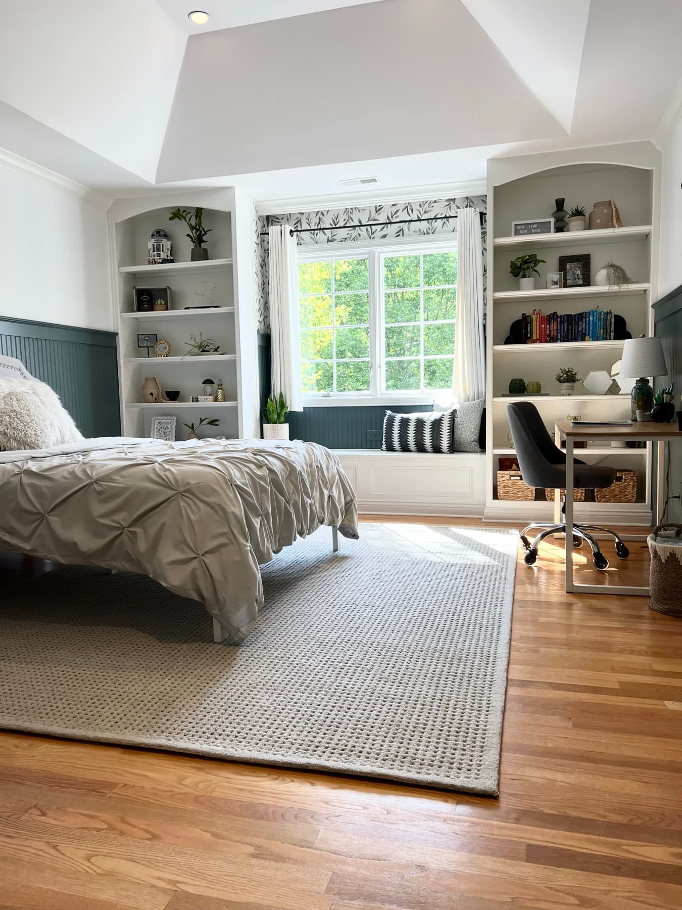 A teen bedroom with custom built-ins around the window, a botanical palette, and layered bedding.