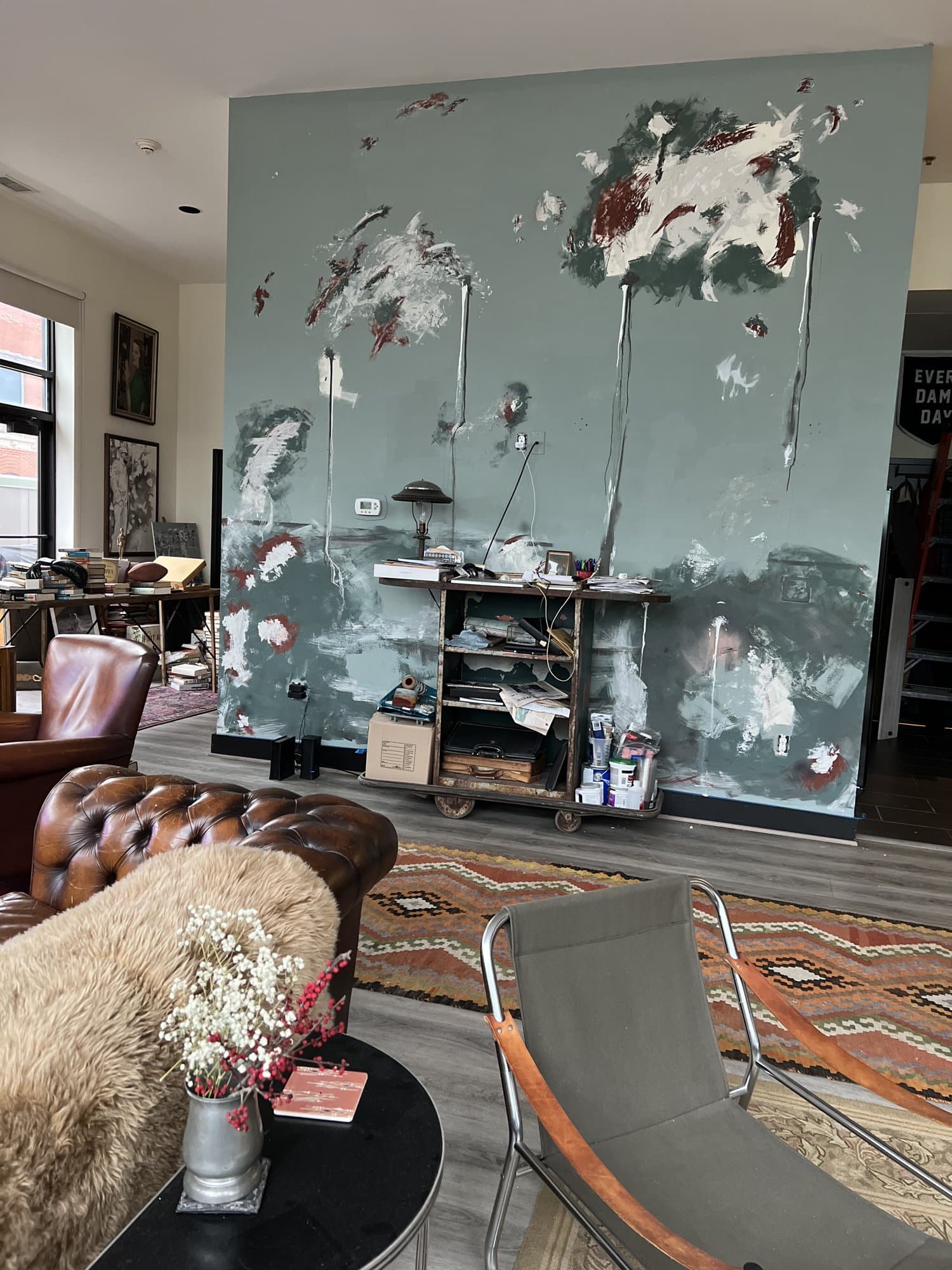 Collide after, a storm-teal hand-troweled plaster wall reading as a backdrop to industrial shelving and a layered persian rug.