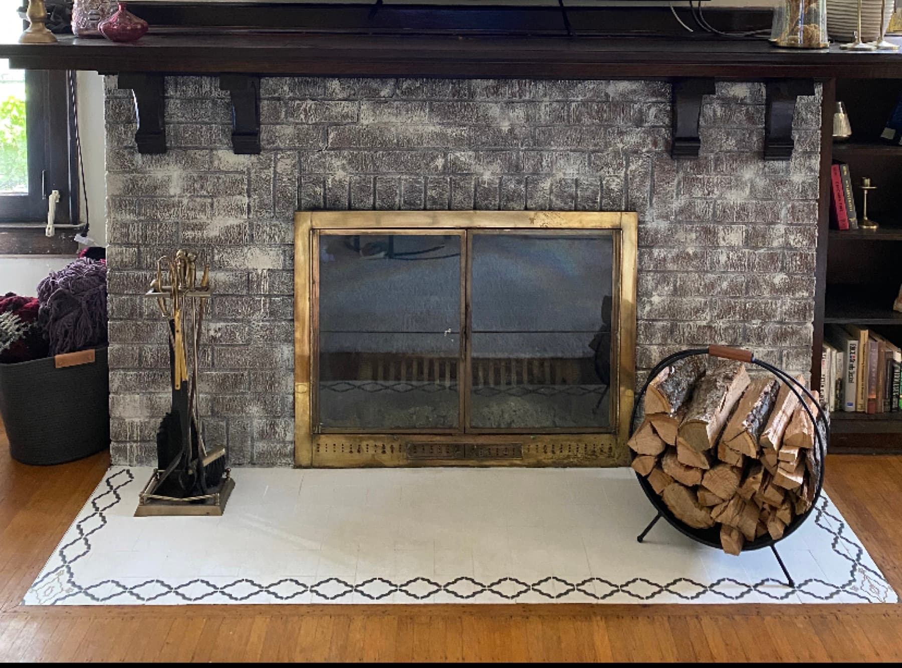 After, a stacked-stone fireplace with a floating mantel, brass screen, and styled hearth.