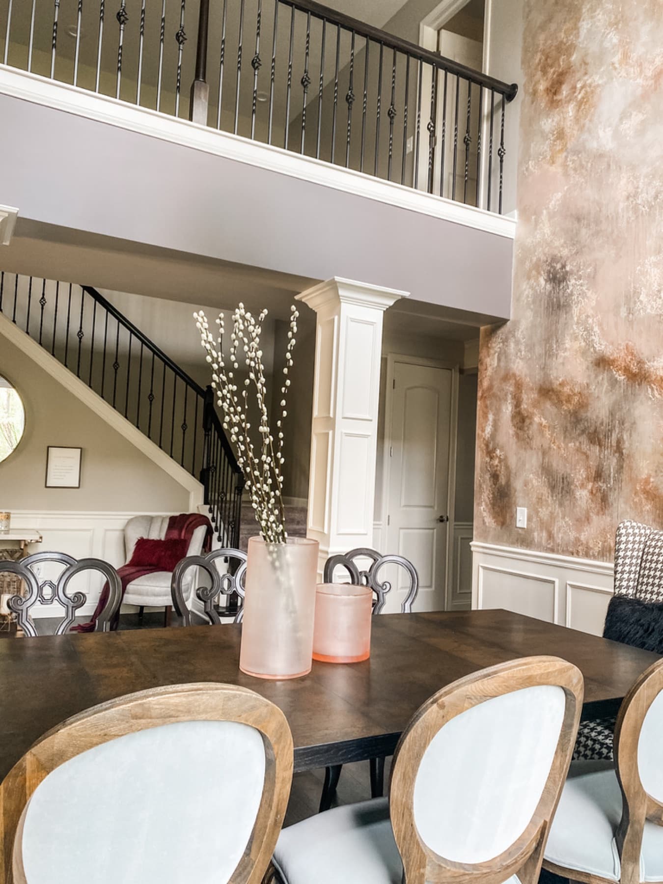 A dining room with a stone feature wall, round upholstered chairs, and a sculptural chandelier.