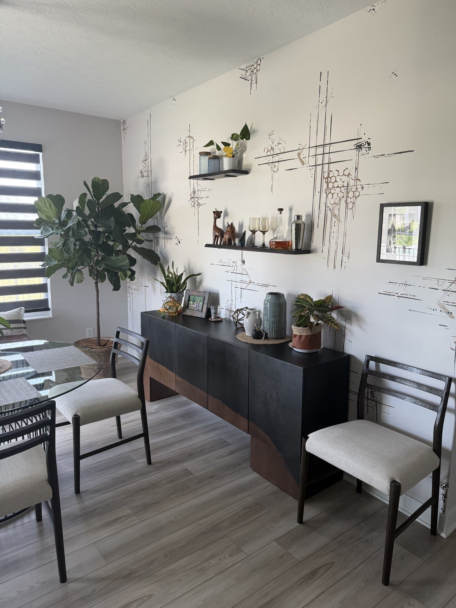 New Normal after, a fine line-drawing mural on bone white behind a walnut sideboard, floating shelves, and a fiddle-leaf fig.