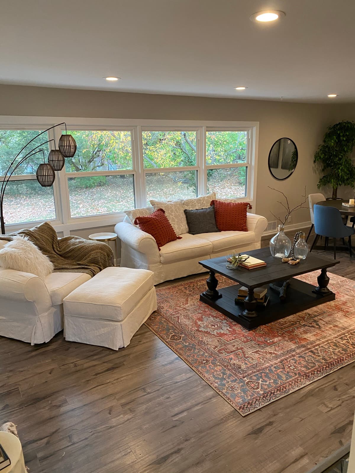 Rural St. living room, white slipcovered sofas, rust accent pillows, and a black baluster coffee table on a faded persian rug.